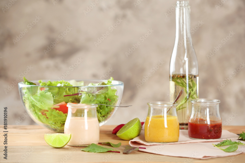 Jars with tasty sauces for salad on table