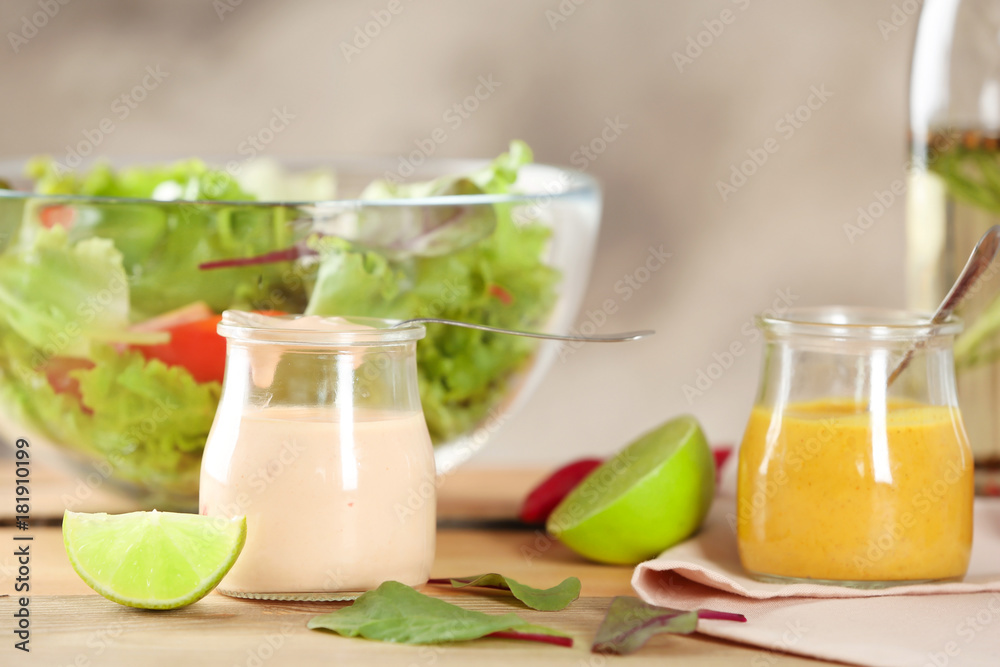 Jars with tasty sauces for salad on table Jars with tasty sauces for salad on table