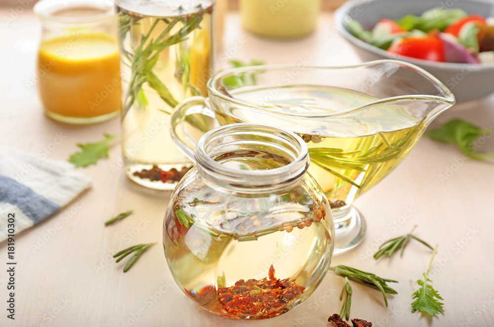 Jar and gravy boat with tasty salad dressings on table