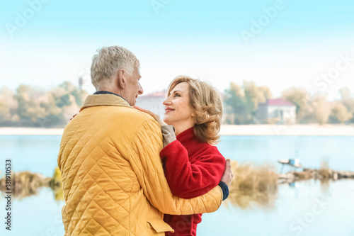 Elderly couple near river on autumn day
