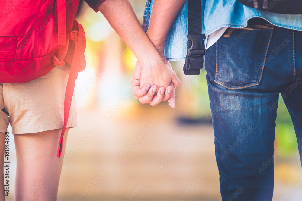 Close up loving couple holding hands while walking happy tourist in the train station of a country after arrival in summer with a warm sunlight background at sunset