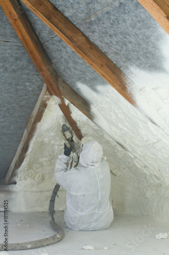 spray polyurethane foam for roof - technician spraying foam insulation using plural component gun for polyurethane foam, inside