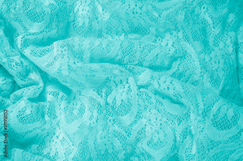 Texture, fabric, background. Lacy turquoise fabric, lace. A thin open fabric, usually cotton or silk, made by a loop, twisting or knitting on patterns and is used specially for trimming clothes.