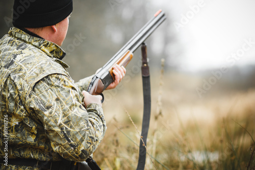 A man with a gun, against the background of an autumn forest.