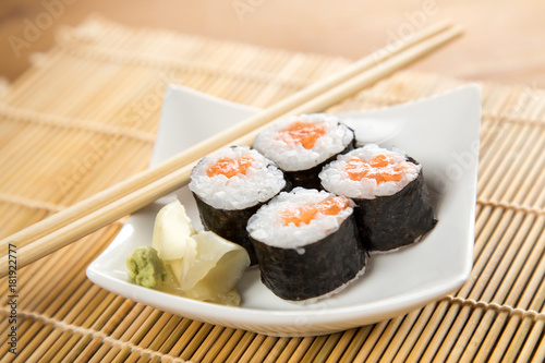 Vier Maki Sushi mit Lachs auf Teller an Holz Stäbchen