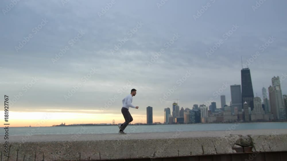 Man starts running from the set position. Man is running on the ebankment. Athlete training outdoors. Downtown with skyscrapers on the background. Man starts running from the set position. Man is running on the ebankment. Athlete training outdoors. Downtown with skyscrapers on the background.