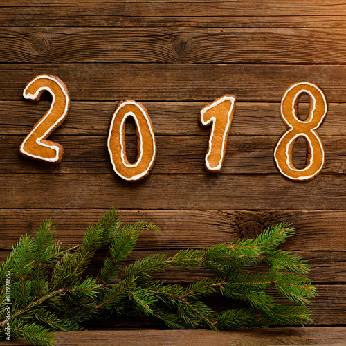 New Year's concept. Figure 2018 from gingerbread, fir branch on a wooden background.