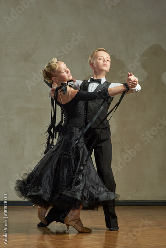 Attractive young couple of children dancing ballroom dance in studio