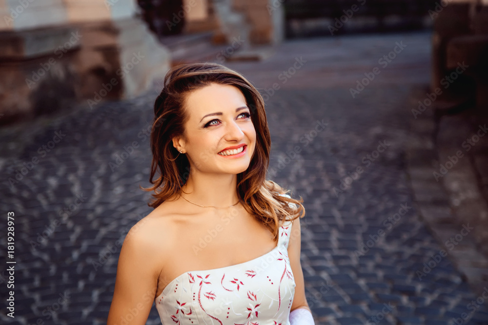 happy bride with a beautiful hairdo smiles against the background of the city