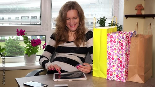 Happy pregnant woman using tablet for online shopping at home photo