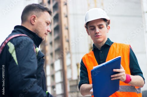 engineer talking discussing with Architect working with blueprints for architectural plan, sketching a project.