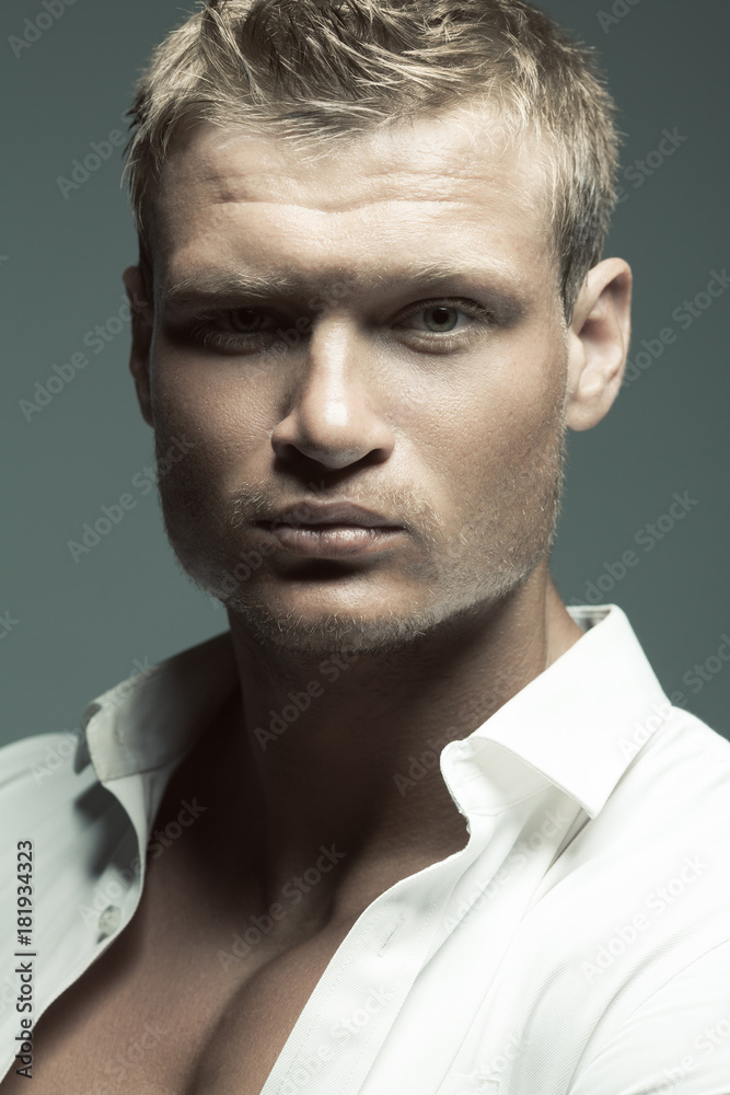 Male fashion, beauty concept. Portrait of brutal young man with short wet blond hair wearing white shirt, posing over gray background. Classic style. Close up. Studio shot Male fashion, beauty concept. Portrait of brutal young man with short wet blond hair wearing white shirt, posing over gray background. Classic style. Close up. Studio shot
