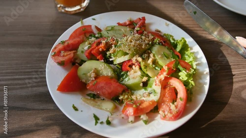 POV view of hands young woman in red dress having dinner in a cafe. Fresh salad with tomatoes, cucumbers, chees