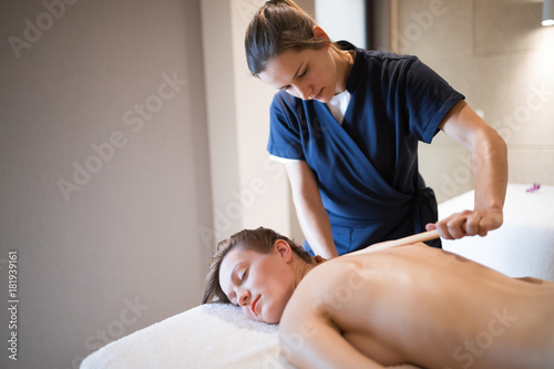 Massage therapist using wooden tool to massage patient