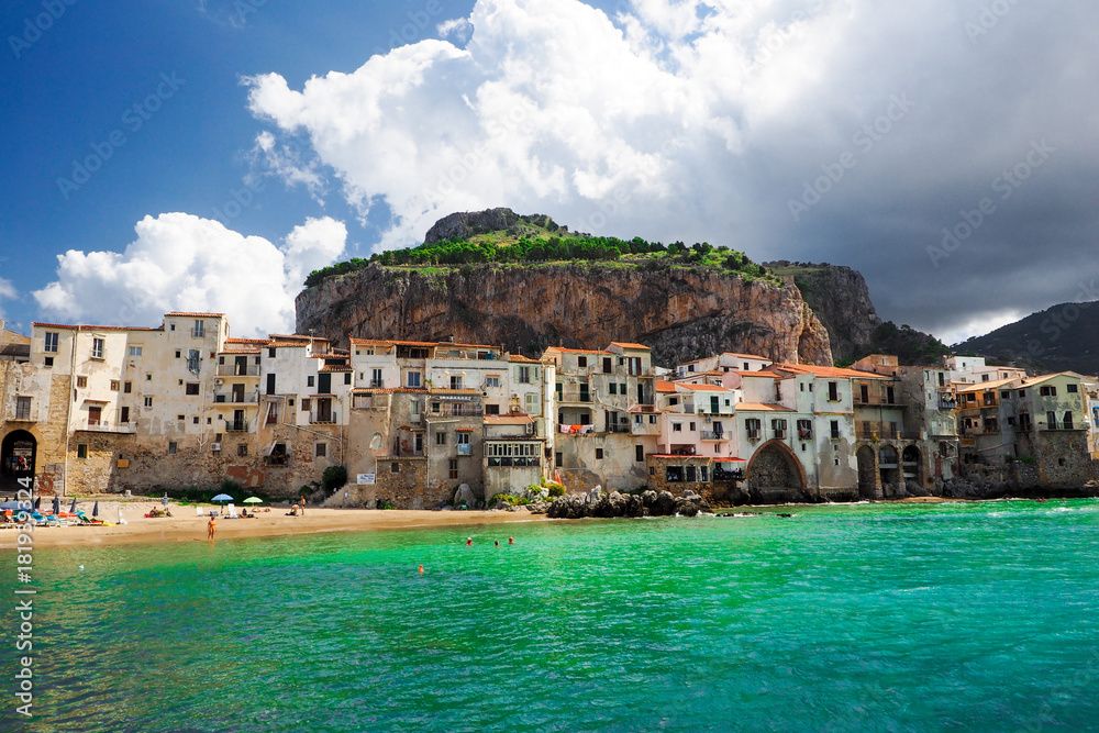Beautiful old harbor with buildings and fortress on the hill in Cefalu, Sicily, Italy.
