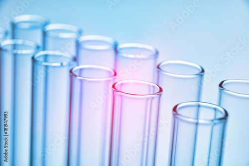 Two rows of empty glass test tubes blue background. Elevated view