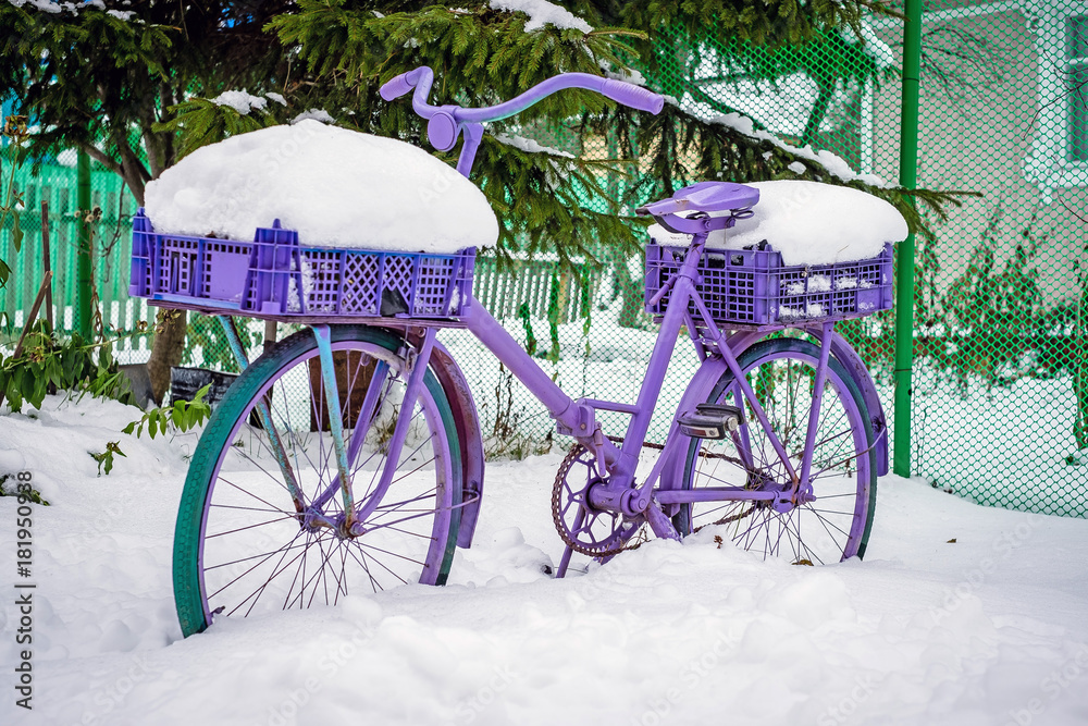 purple bicycle stands under the snow