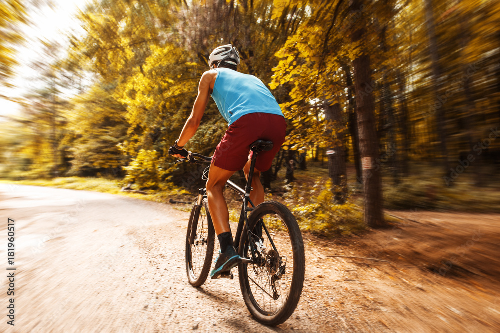 Young man riding a mountain bike on old country road.