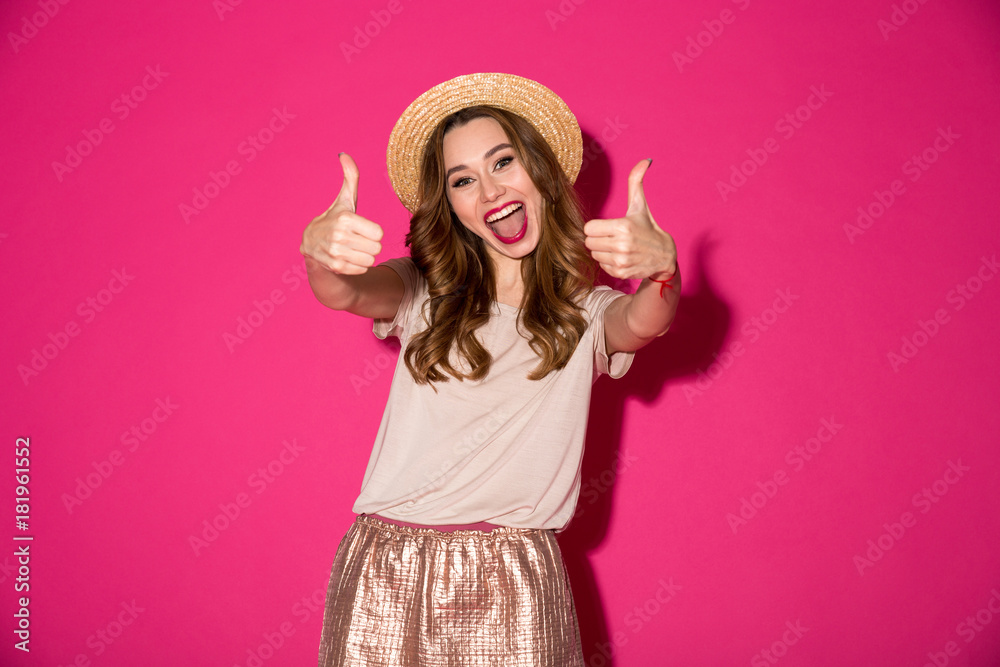 Excited young woman in hat showing thumbs up gesture. Excited young woman in hat showing thumbs up gesture.