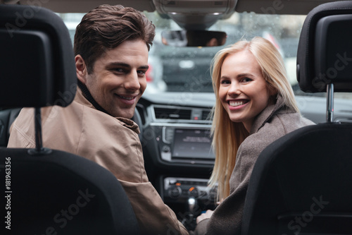 Young loving couple sitting in car looking camera.