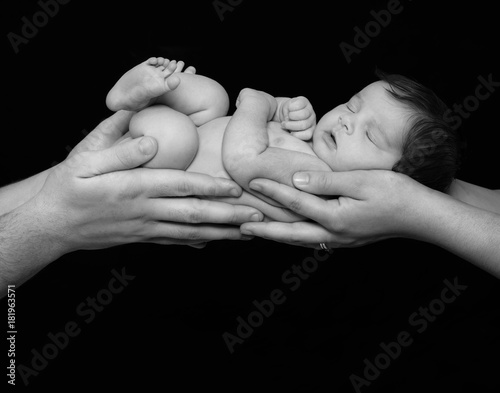 Black and white image of baby asleep in the parents' hands