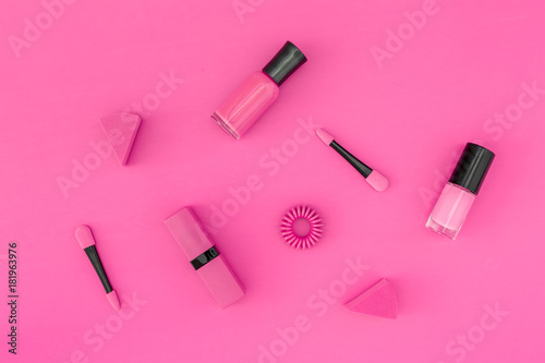 Bright decorative cosmetics. Pink nail polish and lipstick on pink background top view copyspace