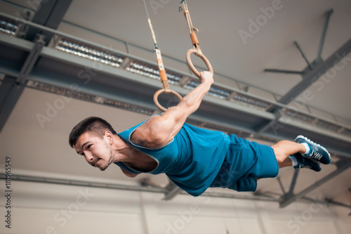 young athlete exercising with gymnastics rings;