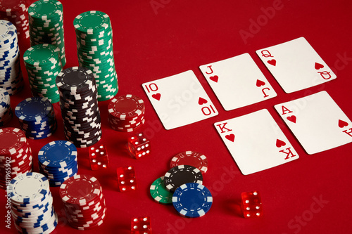 Casino gambling poker equipment and entertainment concept - close up of playing cards and chips at red background. Royal flush heart. photo