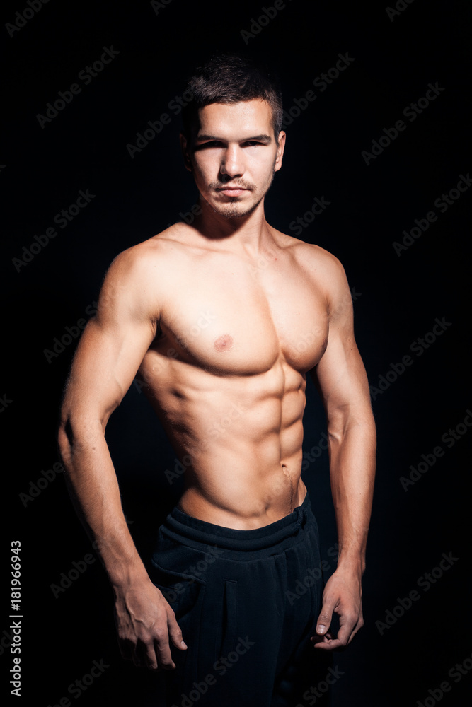 Fototapeta premium młody przystojny mężczyzna z doskonałym tułowiem na czarnym tle;