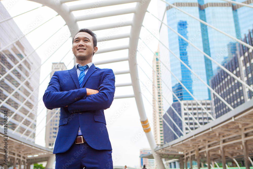 Businessman standing with cross one's arm , with office building background - business success, achievement, and win concepts Businessman standing with cross one's arm , with office building background - business success, achievement, and win concepts