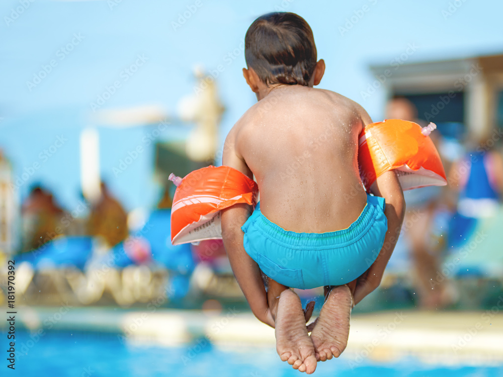 Caucasian boy jumping into the pool.