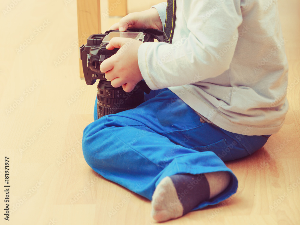 Kid playing with big professional digital camera