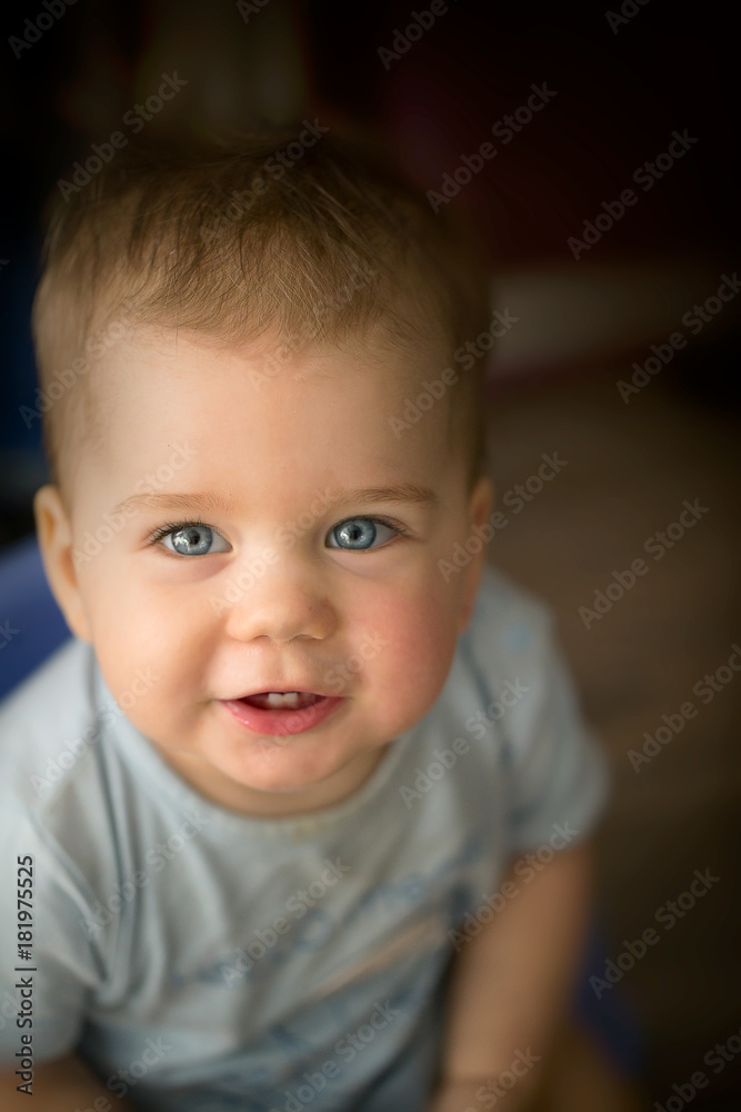 Portrait of a smiling one year old baby looking into the camera. The girl is happy with mouth open. Happy childhood. Funny, light-skinned, cute baby. European type. Blue eyes, blond hair.