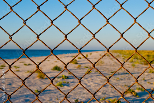a large grid of metal fences a deserted beach wire fence pass forbidden yellow sand blue sea shore clean blue sky summer warmth