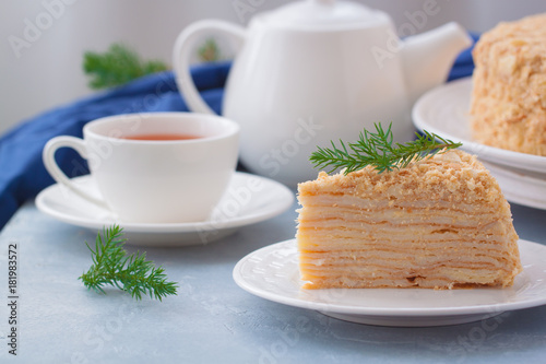 Round multi-layered cake Napoleon with custard, on a light-blue table background. Selective focus. Russian cuisine. photo