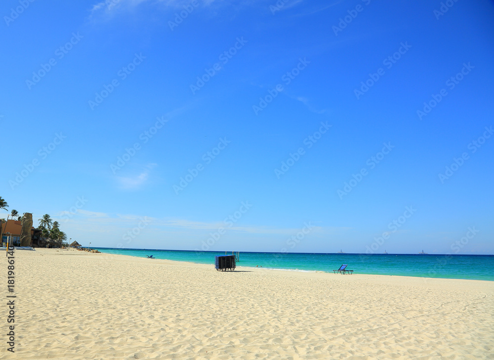 White sand beach and turquoise water  ocean on blue sky background. Aruba. September, 2017. Beautiful backgrounds.