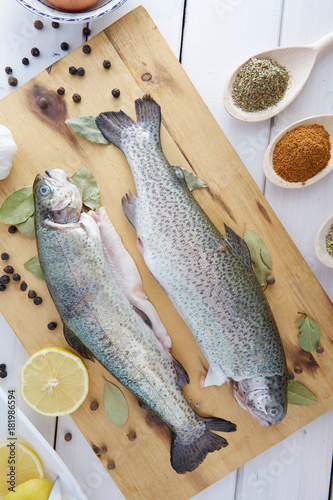 Fresh trout on a wooden board surrounded by spices.  