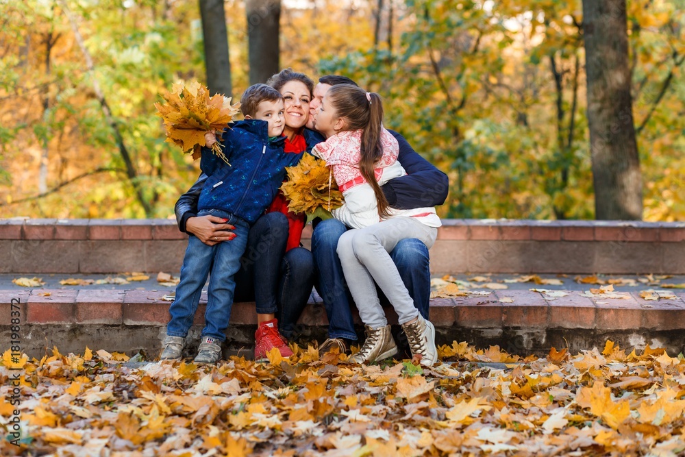 A happy family having fun in the park in autumn walking and hugging. Family, love, happiness concept. Family of four with mother father sister and a little cute brother A happy family having fun in the park in autumn walking and hugging. Family, love, happiness concept. Family of four with mother father sister and a little cute brother