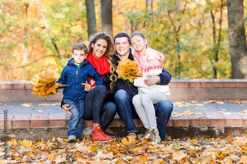 A happy family having fun in the park in autumn walking and hugging. Family, love, happiness concept. Family of four with mother father sister and a little cute brother