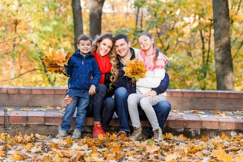 A happy family having fun in the park in autumn walking and hugging. Family, love, happiness concept. Family of four with mother father sister and a little cute brother