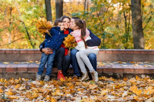 A happy family having fun in the park in autumn walking and hugging. Family, love, happiness concept. Family of four with mother father sister and a little cute brother