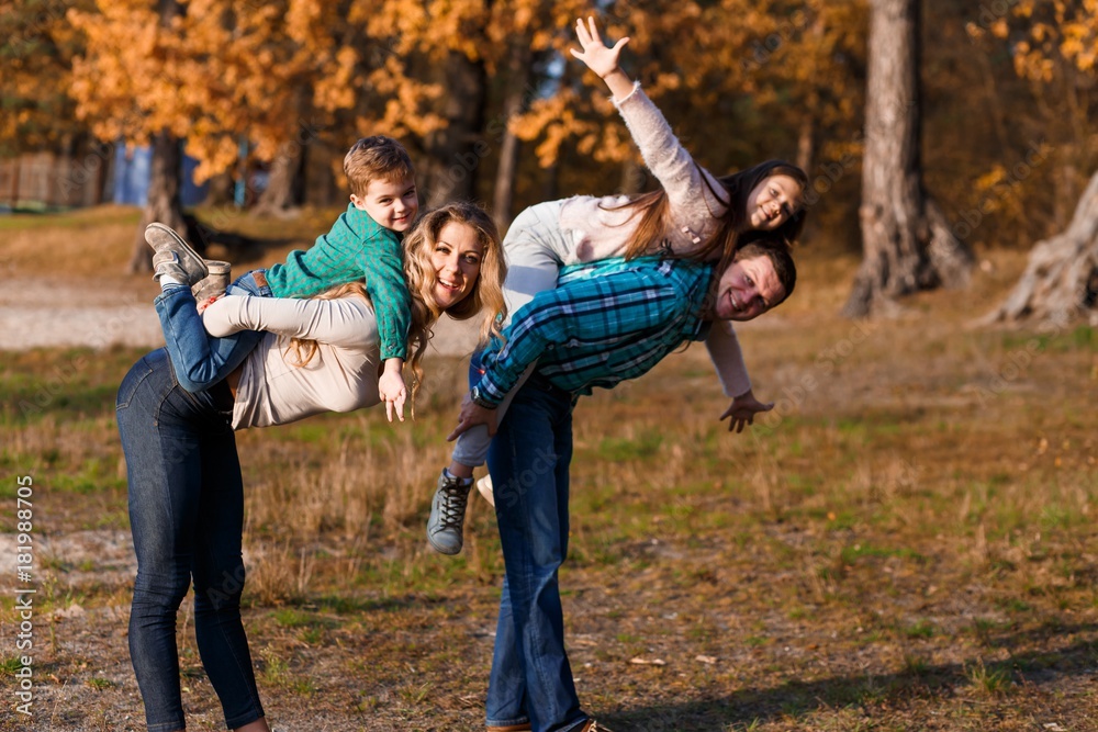 A happy family having fun in the park in autumn walking and hugging. Family, love, happiness concept. Family of four with mother father sister and a little cute brother A happy family having fun in the park in autumn walking and hugging. Family, love, happiness concept. Family of four with mother father sister and a little cute brother