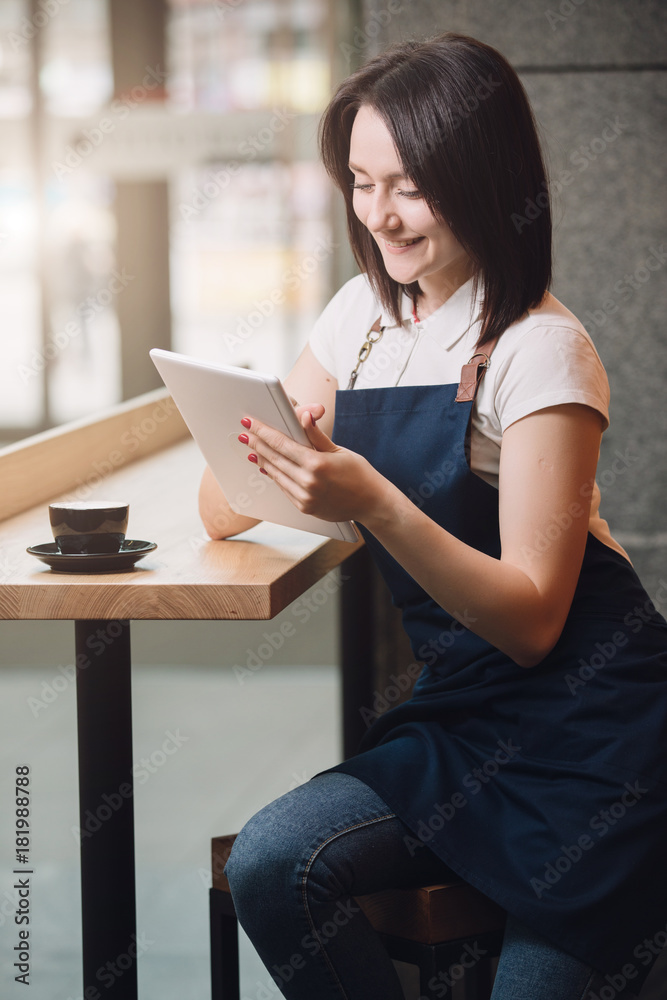 Barista having coffee break, she using tablet PC Barista having coffee break, she using tablet PC