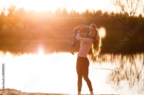 Mother and sun having fun at sunset in autumn near the river. A happy family and active lifestyle concept © Gorodetskaya