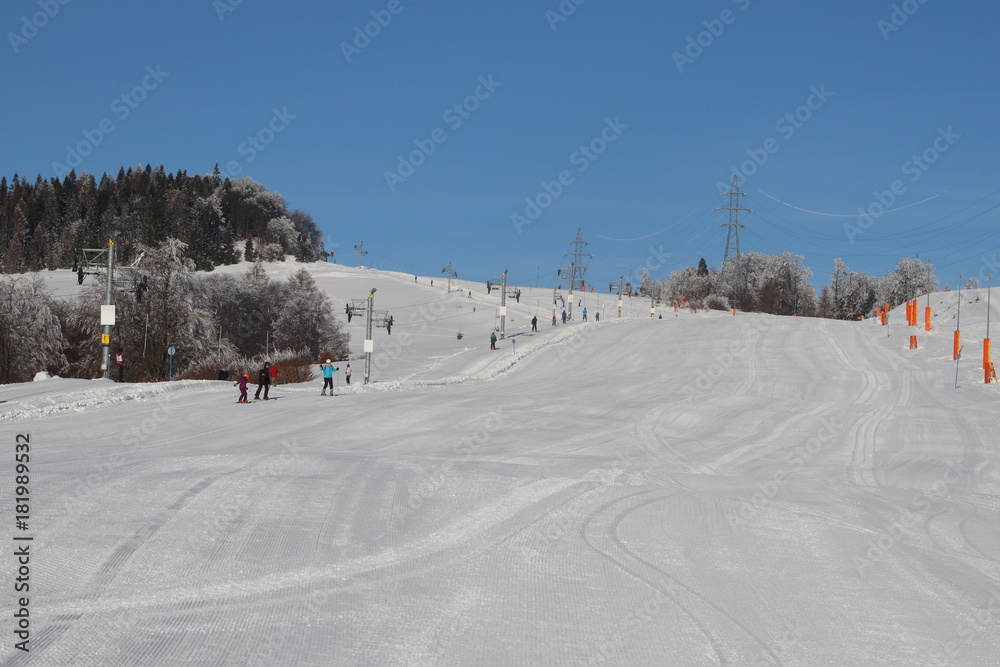 Ski slope with silhouettes of people in the distance on a beautiful snowy day Ski slope with silhouettes of people in the distance on a beautiful snowy day