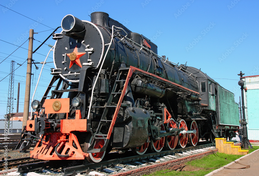 Old black locomotive in the railway depot in the parking lot