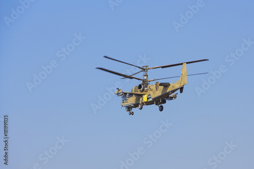 Green helicopter flies against the blue sky
