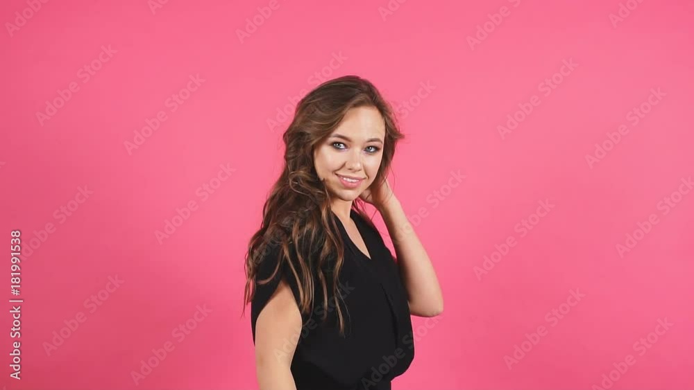 Pretty cheerful girl with flying curly hair smiling laughing looking at camera over white background. Slow motion. Pretty cheerful girl with flying curly hair smiling laughing looking at camera over white background. Slow motion.