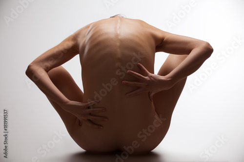 Картината върху платно Naked female figure sitting on the ground seen from the back.