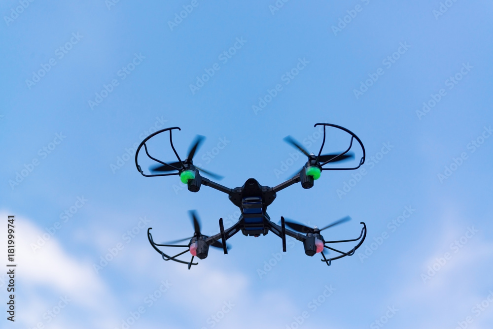 Flying drone of quad copter in blue sky.